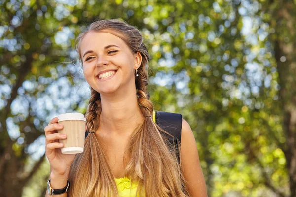 Веселая студентка держит кофе на открытом воздухе — стоковое фото