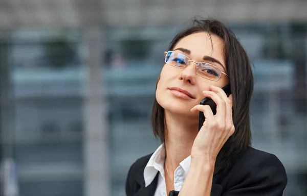 Kieliszek całkiem młoda kobieta za pomocą jej telefon komórkowy, stojąc na ulicy. — Zdjęcie stockowe