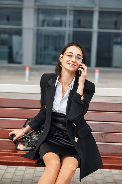 Une photo d'une jolie jeune femme utilisant son téléphone portable alors qu'elle se tenait dans la rue . — Photo