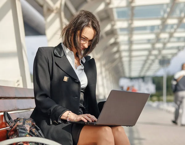 Kobieta biznesu za pomocą laptopa siedząc przy ulicy zielonej nowoczesnego miasta. — Zdjęcie stockowe