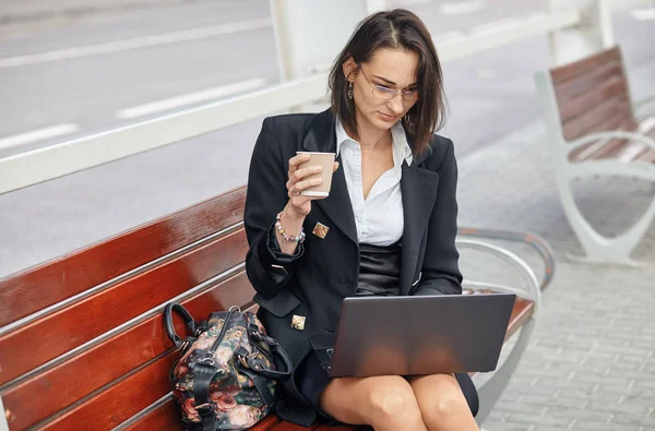 緑豊かなモダンな街に座りながらノート パソコンを使用してビジネスの女性. — ストック写真