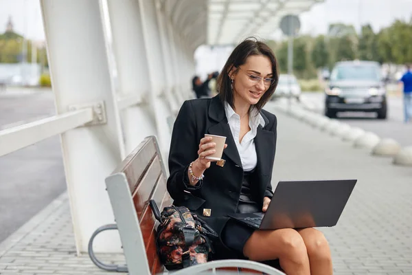 Kobieta biznesu za pomocą laptopa siedząc przy ulicy zielonej nowoczesnego miasta. — Zdjęcie stockowe