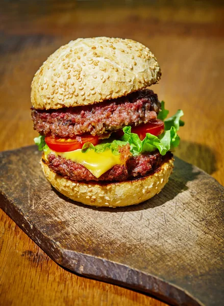 Hamburger con manzo, formaggio e verdure su fondo rustico in legno — Foto Stock