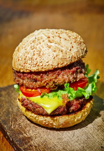 Hamburger con manzo, formaggio e verdure su fondo rustico in legno — Foto Stock