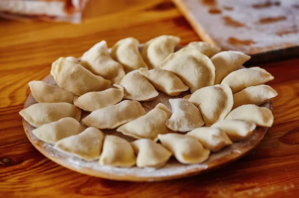 Dumplings raw on a wood board. The process of cooking — Stock Photo, Image