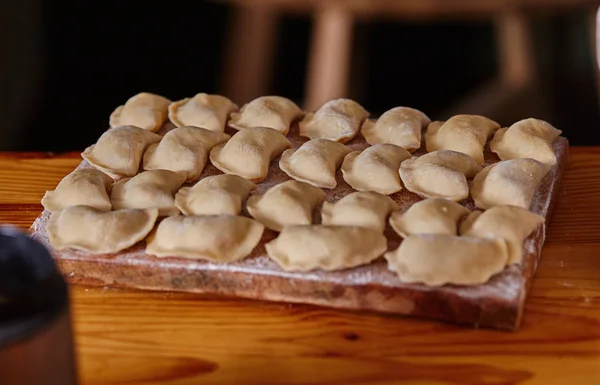 Dumplings raw on a wood board. The process of cooking — Stock Photo, Image