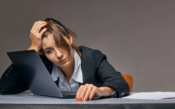 疲れている女性がノート パソコン前のテーブルに座っています。 — ストック写真