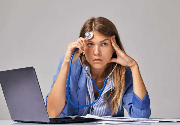 Concepto de problemas en el trabajo. Una trabajadora, mirando hacia arriba, se escucha a sí misma usando un fonendoscopio — Foto de Stock