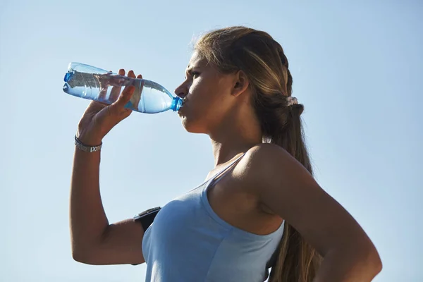 Nahaufnahme Porträt einer attraktiven jungen Frau, die Wasser aus der Flasche trinkt. — Stockfoto