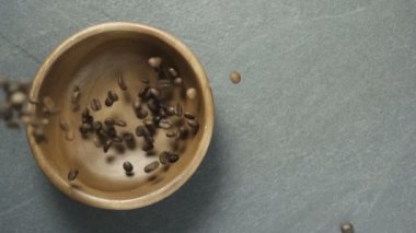 Kavrulmuş kahve çekirdekleri masadaki ahşap kaseye düşüyor. Yavaş Hareket