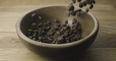 Kavrulmuş kahve çekirdekleri masadaki ahşap kaseye düşüyor. Yavaş Hareket