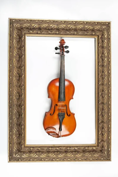 小提琴和金色的框架在一个独立的工作室后台 — 图库照片