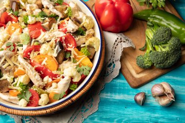 Eski ahşap bir masada kızarmış tavuk ve sebze.