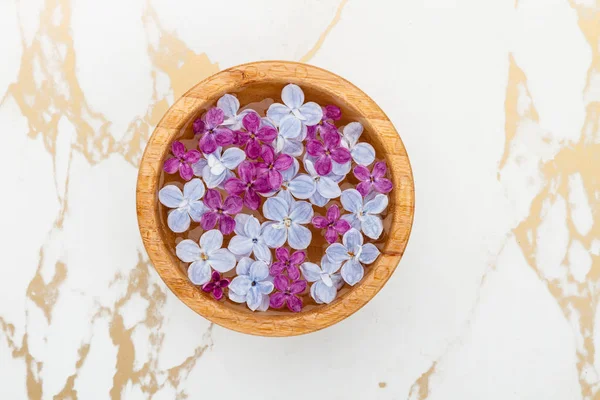 Flutuante flores lilás em uma tigela de água no fundo de mármore — Fotografia de Stock