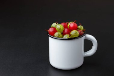 Beyaz metal bardakta olgun kırmızı ve yeşil bektaşi üzümü.