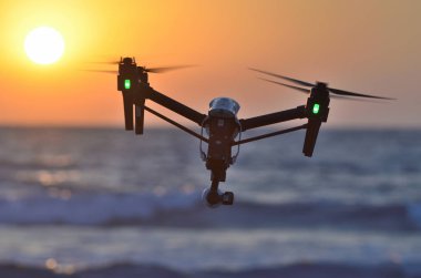 deniz günbatımı arka plan üzerinde quadcopter silüeti