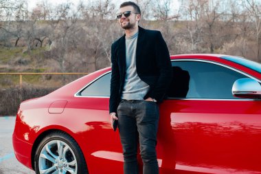 Kırmızı araba ile bir akıllı telefon olan açık portre adam