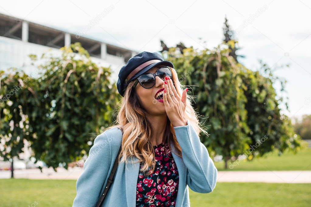 Attractive young blonde woman wearing sunglasses and posing in modern city