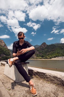 Açık güneşli günde smartphone kullanarak güneş gözlüklü adam portresi