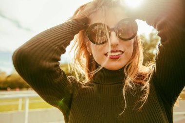 Güneş gözlüklü gülümseyen genç kadın portresi