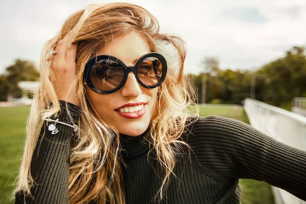 Güneş gözlüklü gülümseyen genç kadın portresi