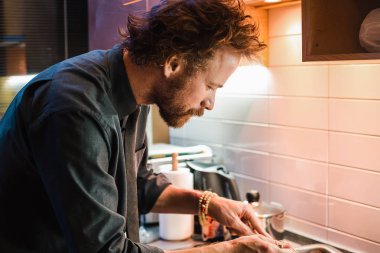 Yemek yemek mutfakta kıvırcık saçlı Genç adam