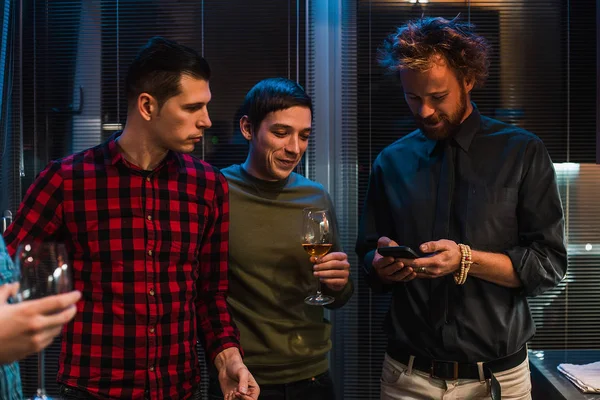 Guys drinking wine and using smartphone indoor