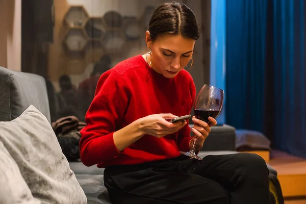 Porträtt Kvinna Röd Jumper Dricker Vin Och Med Smartphone — Stockfoto
