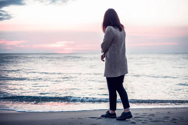 Kadın ceket ve pantolon gece karanlığında deniz kenarında yürüyüş