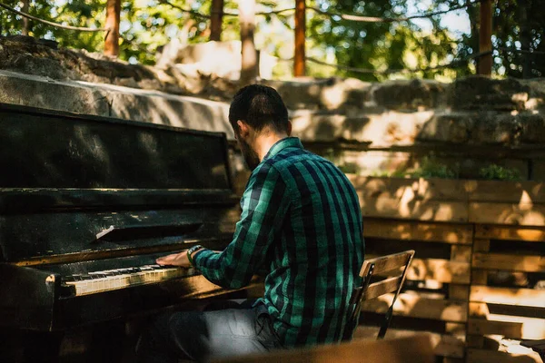 Young man playing on piano in city park at daytime