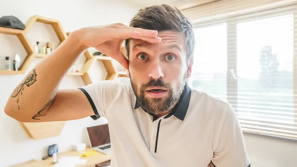 handsome bearded man with facial expression holding his hand on forehead looking for something