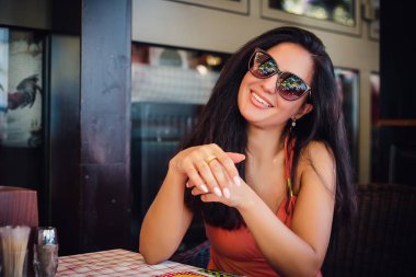 açık kafe güneş gözlüğü takıyor masada oturan gülümseyen esmer kadın portresi