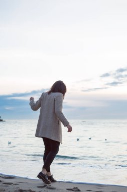 kumsalda, arkadan görünüm yürüyüş gri ceket şık esmer kadına tam uzunlukta portresi