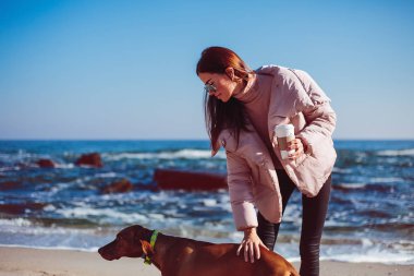 Kahve tutarak ve köpekle oynamayı genç kadın