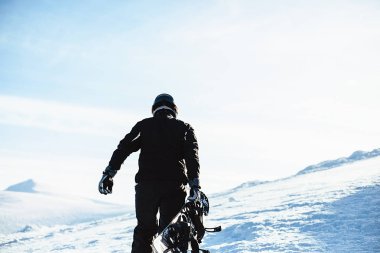 Dağlarda snowboard yapan arka plandaki adam.