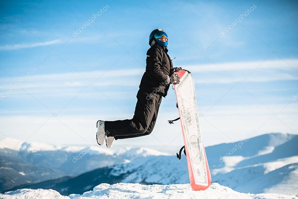 Happy man jumps with snowboard in mountains 
