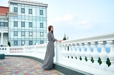 Şehirdeki caddede poz veren uzun elbiseli güzel esmer kadın. 