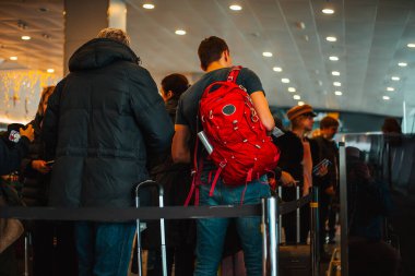 Bir grup insan biniş kapısında kuyrukta bekliyor.