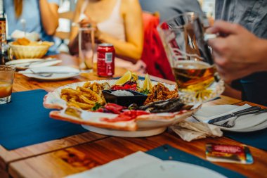 Arkadaşlar birlikte yemek ve bira içerken eğleniyorlar.