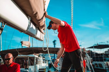 Erkekler güneşli bir günde yatta iplerle çalışıyorlar.