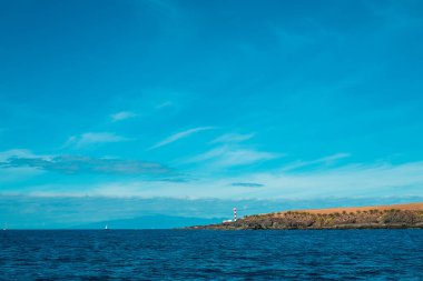 Deniz fenerinin yaz günü kayalık sahil ve deniz manzarası
