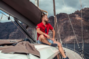 Mutlu sakallı adam güneşli bir günde yatta dinleniyor.