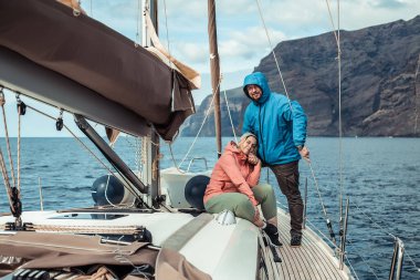 Mutlu sakallı adam ve kadın güneşli bir günde yatta dinleniyorlar.