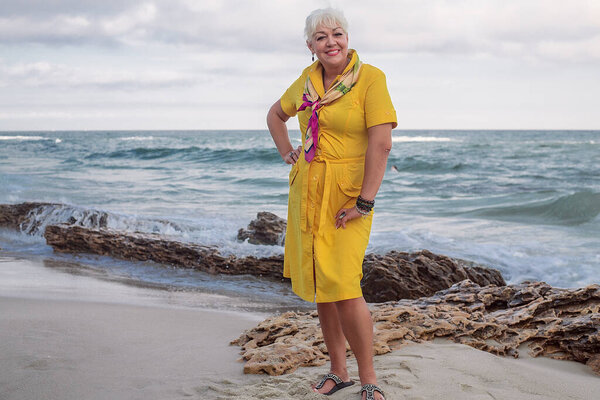 beautiful adult woman with hairstyle and makeup in yellow dress posing on seashore 