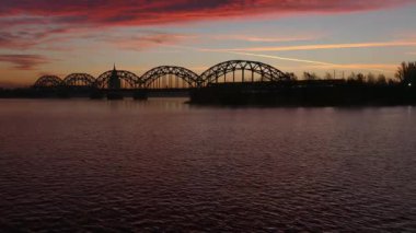 Nehir Daugava üzerinde Riga demir demiryolu köprüsünde gündoğumu