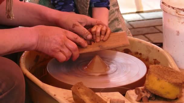 Гончары руки направляющие ребенка на керамическое колесо — стоковое видео