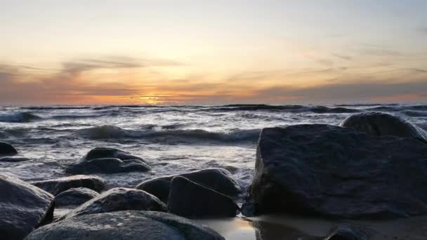 Havsvågor kraschar på stora stenar under solnedgången — Stockvideo