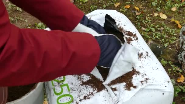 Садовник получает почву из открытого мешка торфа — стоковое видео