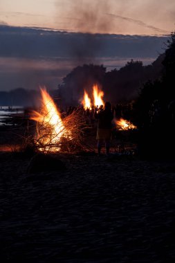 Tanınmayan insanlar yaz gündönümünü sahilde büyük şenlik ateşleriyle kutluyorlar.