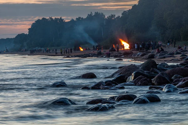 Pessoas irreconhecíveis comemorando o solstício de verão com fogueiras na praia — Fotografia de Stock